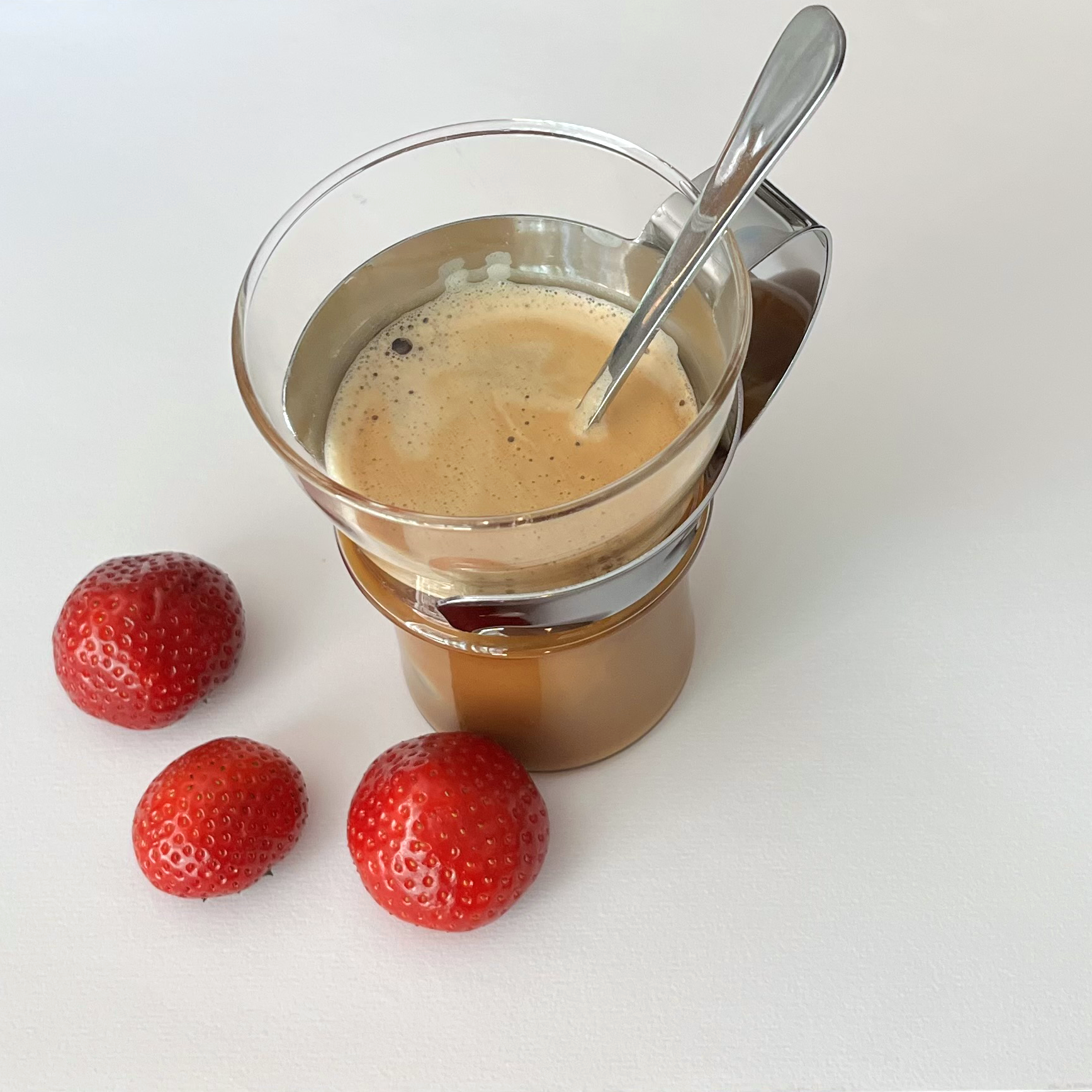 Coffee in a glass container with three strawberries